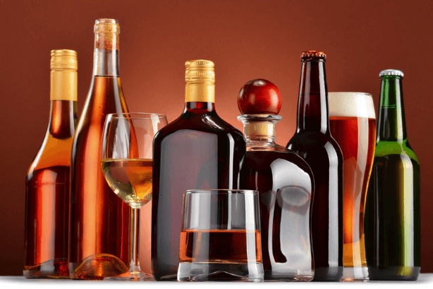 A close up image of alcohol bottles and glasses sitting on a table