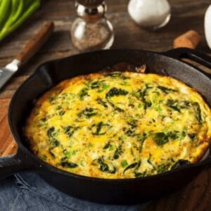 A close up image of a frittata made with asparagus and mushrooms in the cast iron skillet the dish was cooked in.