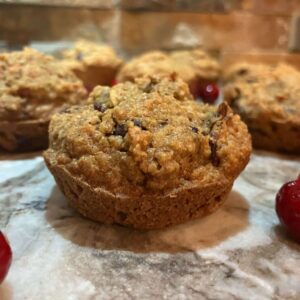 An up-close image of apple cranberry muffins on a granite countertop surrounded by cranberries